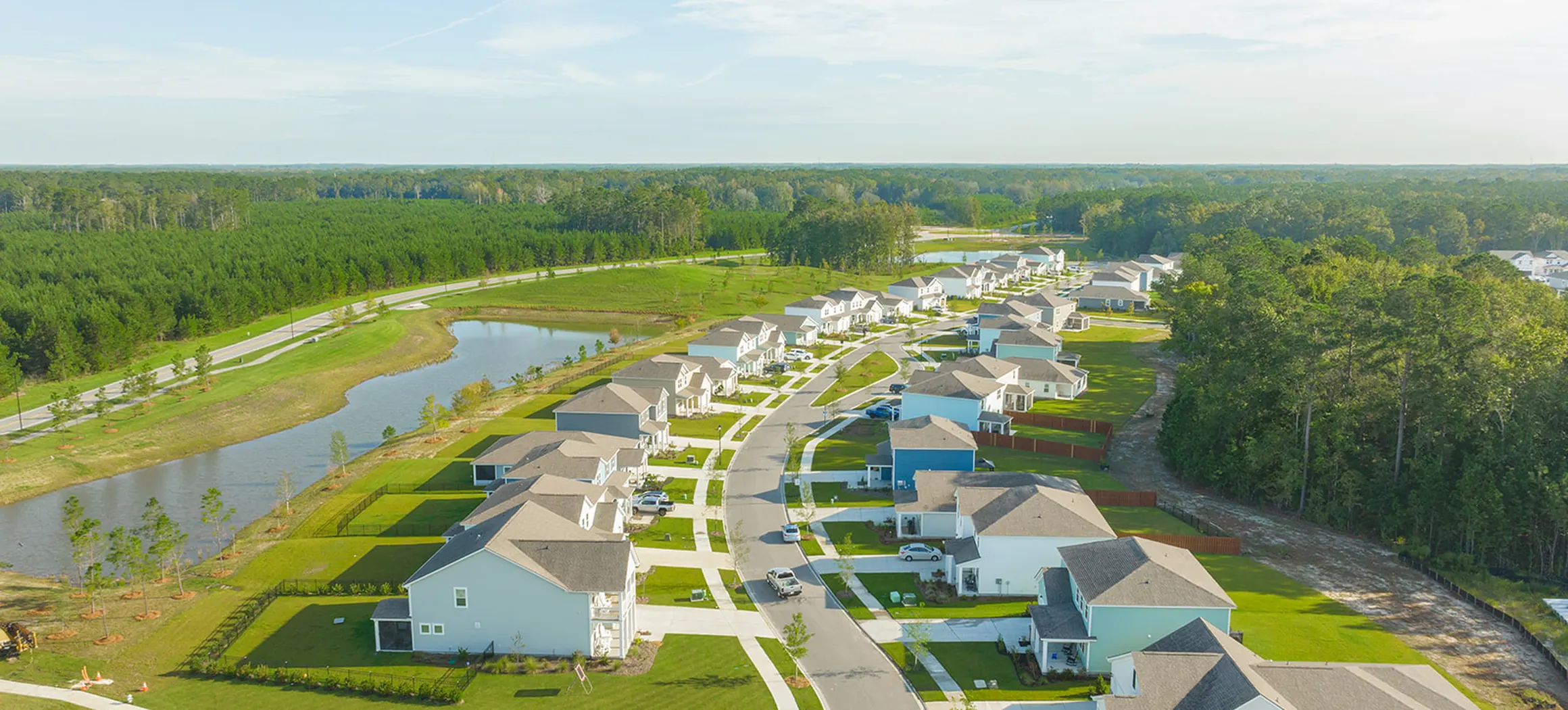 Vista aérea de una calle de Heartwood con casas nuevas junto a un estanque