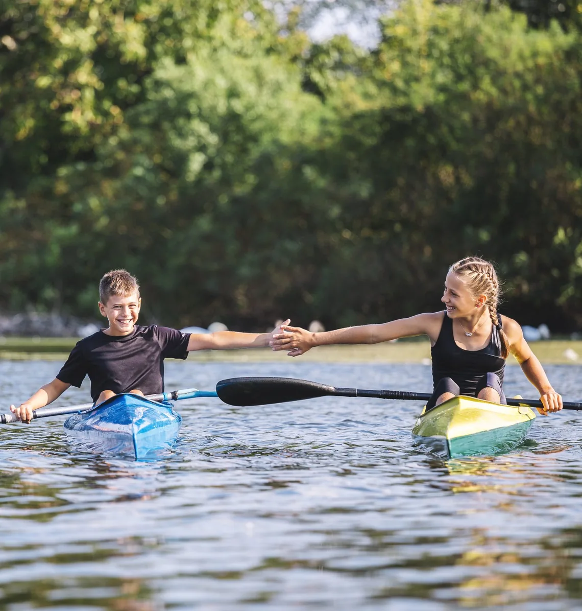 Two kayakers meeting paddles on the river
