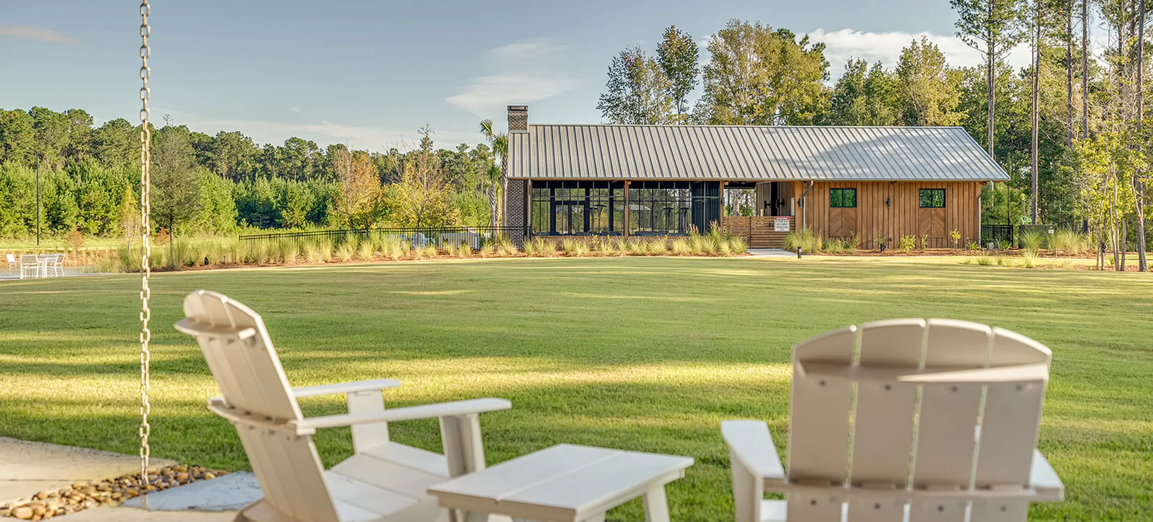 El club de The Outfitters visto desde el césped, con sillas Adirondack en primer plano