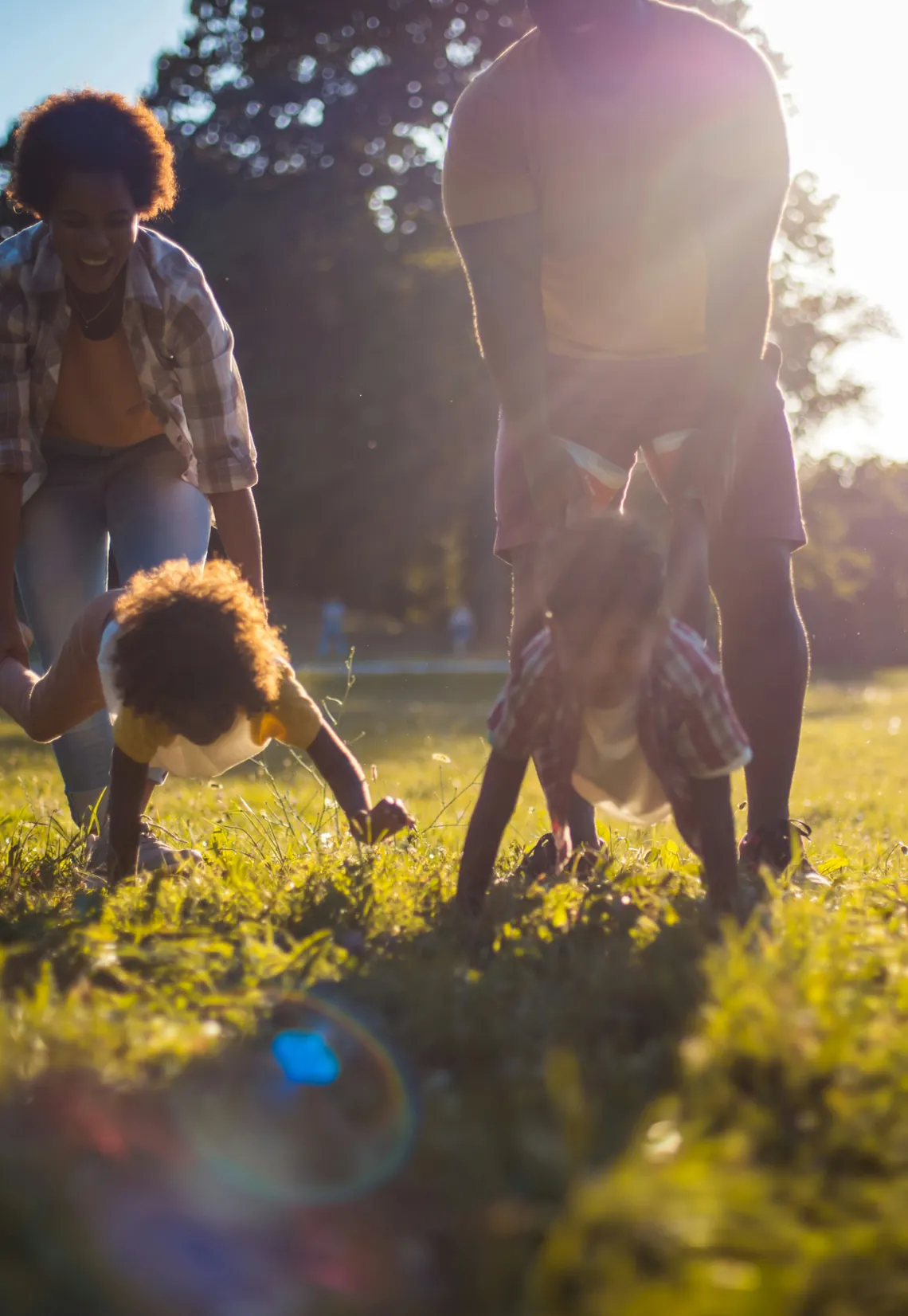Una familia jugando en la hierba a contraluz, al atardecer