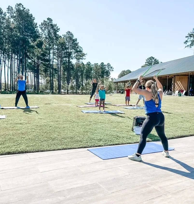 Clase de yoga al aire libre frente al pabellón de The Outfitters
