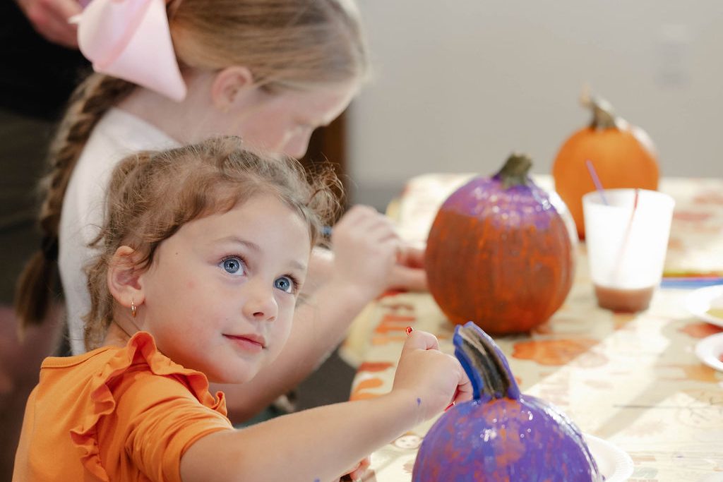 Smiling little girl next to her purple painted pumpkin Smiling little girl next to her purple painted pumpkin