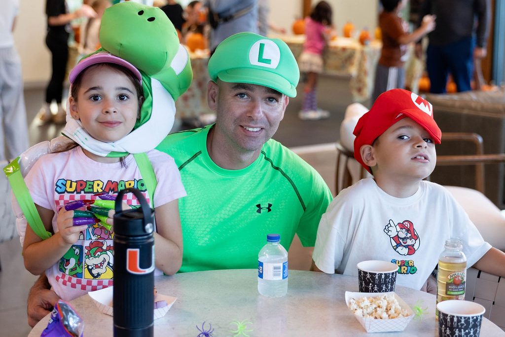 Father and kids in Mario, Luigi and Yoshi costumes at a table Father and kids in Mario, Luigi and Yoshi costumes at a table