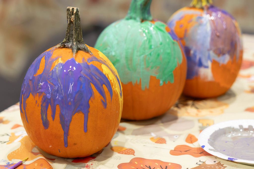 Three painted pumpkins with dripping purple and green paint Three painted pumpkins with dripping purple and green paint