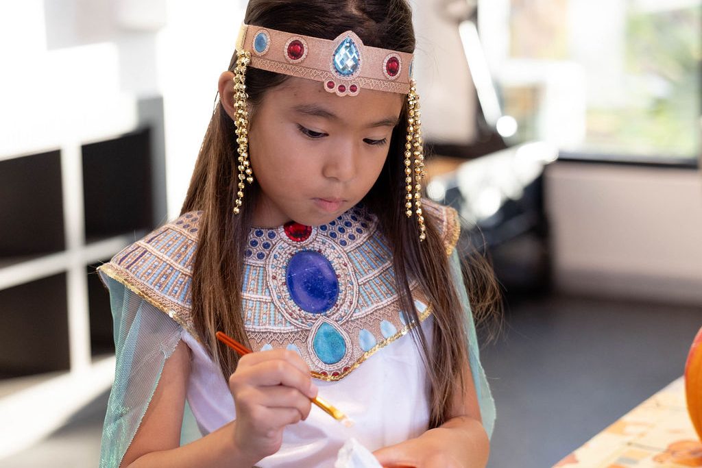 Girl in an Egyptian princess costume painting a pumpkin Girl in an Egyptian princess costume painting a pumpkin