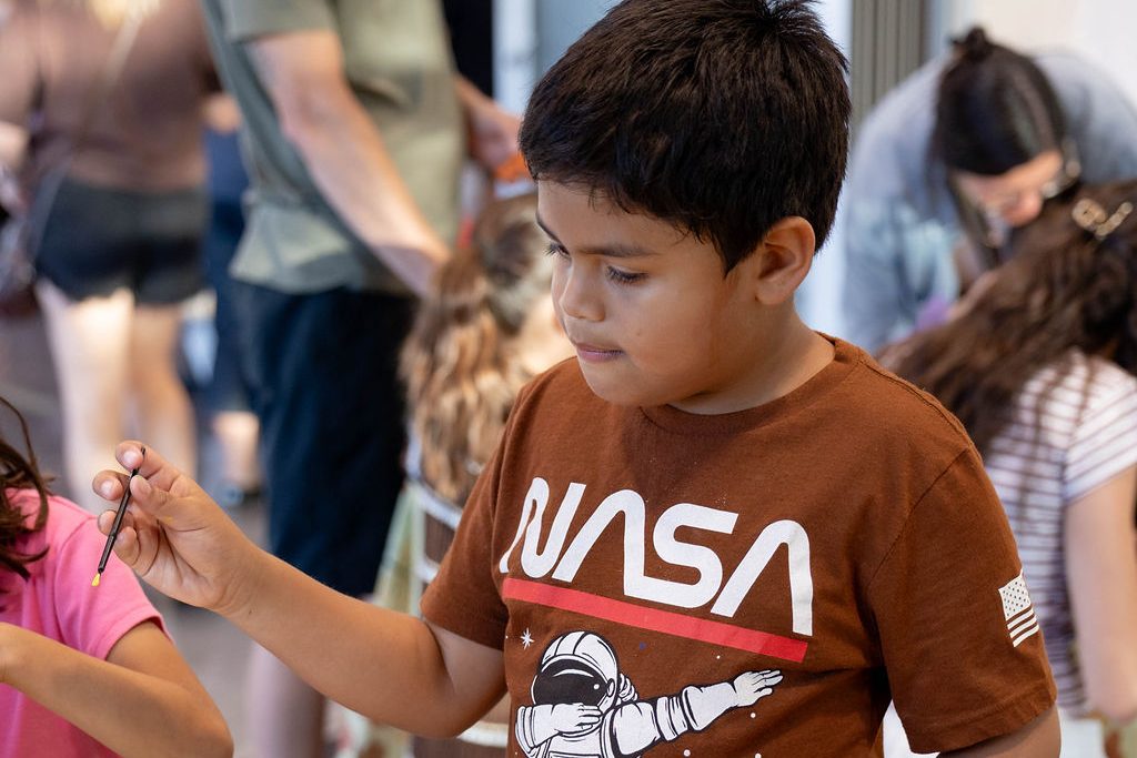 Boy in a NASA shirt painting a pumpkin Boy in a NASA shirt painting a pumpkin