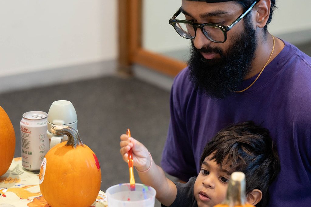 Father helping his son paint a pumpkin Father helping his son paint a pumpkin