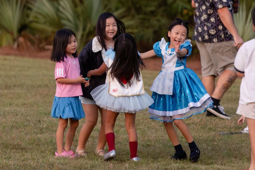 Girls in princess costumes playing on the lawn at sunset Girls in princess costumes playing on the lawn at sunset